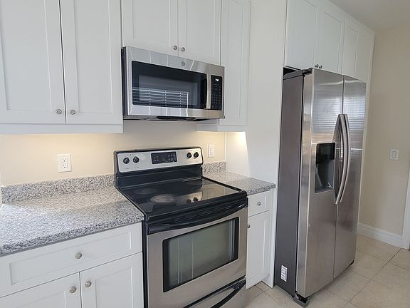 New kitchen showing undercabinet lighting, stainless steel range microwave and refrigerator.