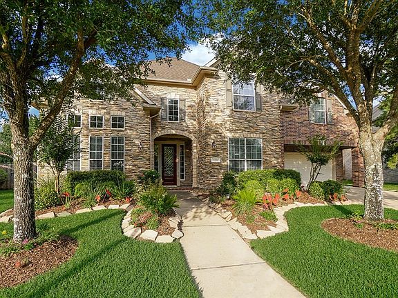 Beautiful curb appeal with a brick and stone exterior and mature landscaping.