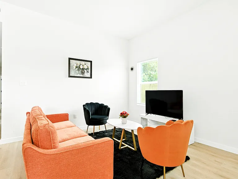 Living room with high ceilings, large window, and seating area centered around a TV and coffee table.