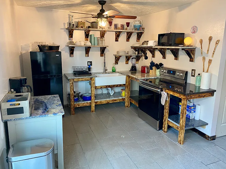 Kitchen is fully stocked with dishes, pots and pans, and cooking utensils.