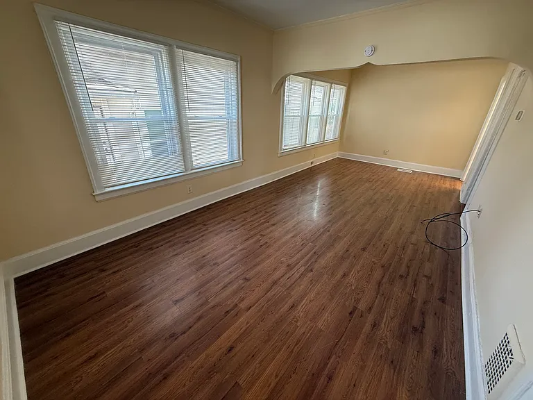 Living room, looking rear. Windows overlook the landscaped pathway to the rear of the building. All windows have brand new blinds, installed in 2025. All walls and molding throughout the unit were painted in early 2025.