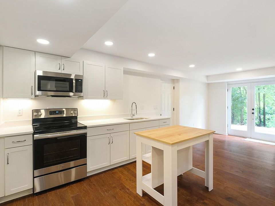 Renovated open-concept kitchen and living area with private patio access and wooded views.