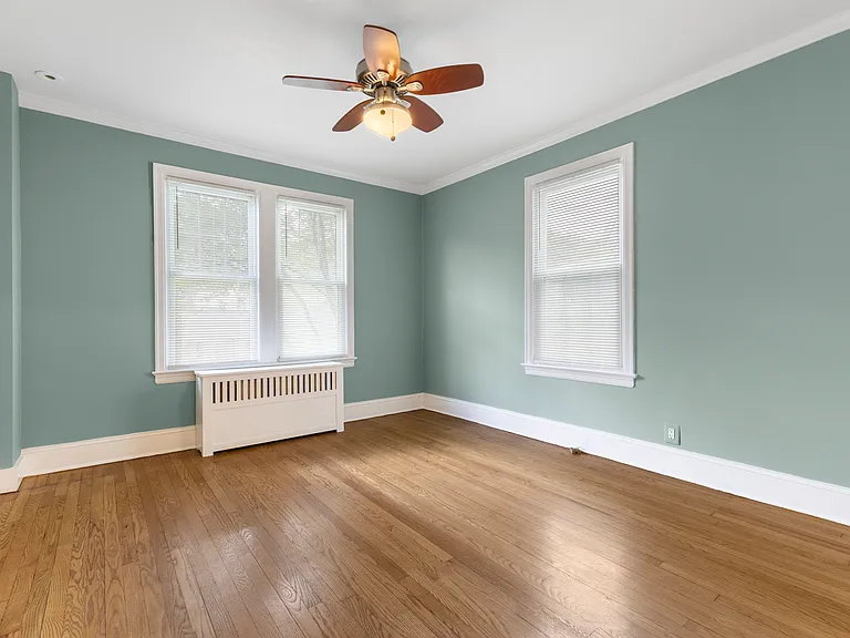 Bright and airy upstairs bedroom featuring classic hardwood floors and fresh paint.