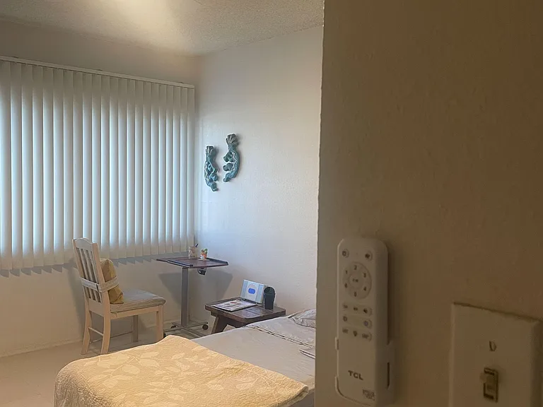Private bedroom with a furnished bed, and control remote for ceiling fan.