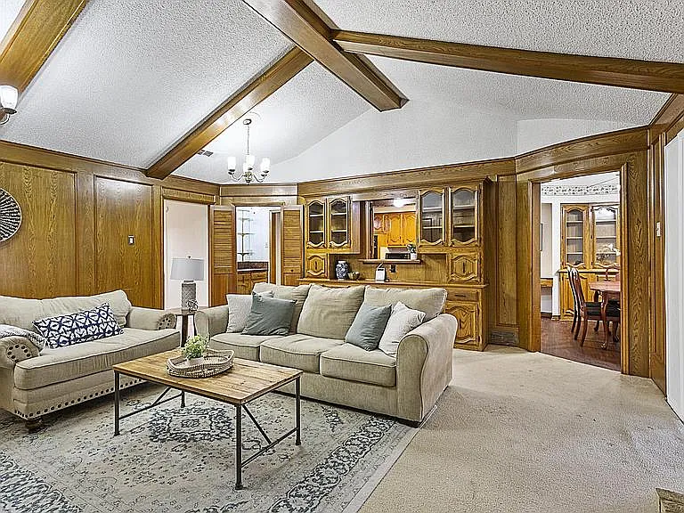 Spacious living area with vaulted ceilings, built-in wood cabinetry, and a comfortable layout that flows into dining and kitc