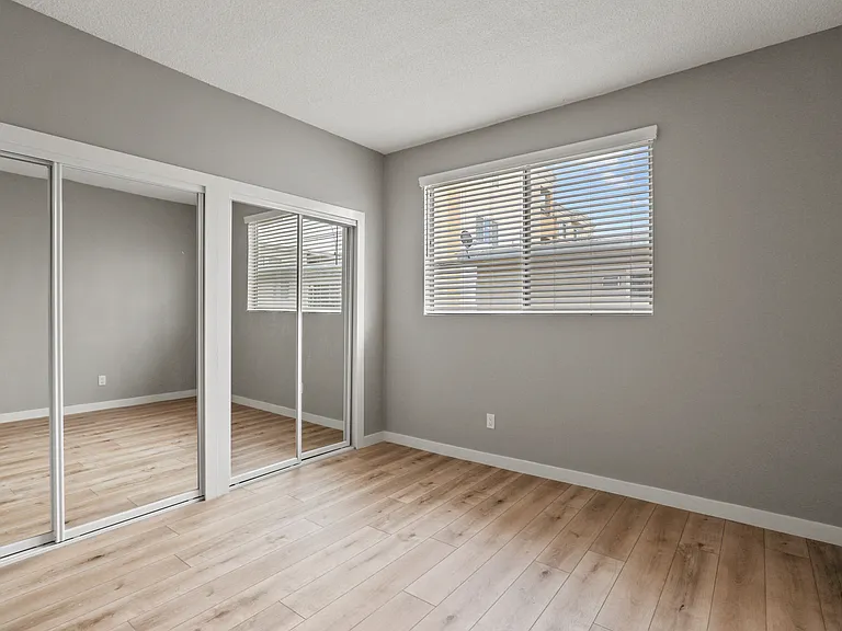 Bedroom with Double Mirrored Closets, Vinyl Flooring, and Window