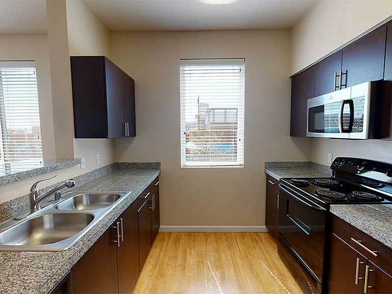 Apartment kitchen with wood-style flooring.