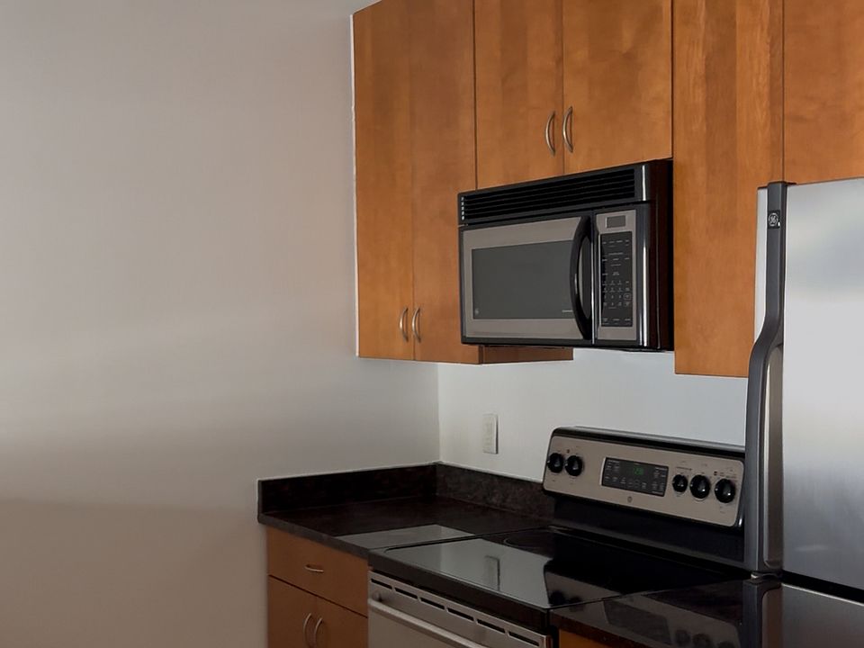 Full-sized kitchen with microwave, oven, fridge, and dishwasher, plus ample storage on both sides and a built-in 4-top bar seating area.