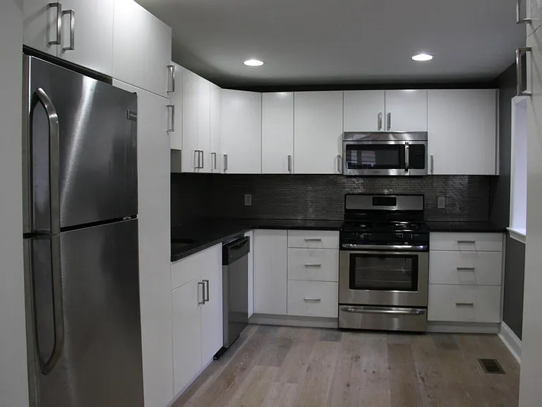 Kitchen with silver tile backsplash and stainless steel appliances.