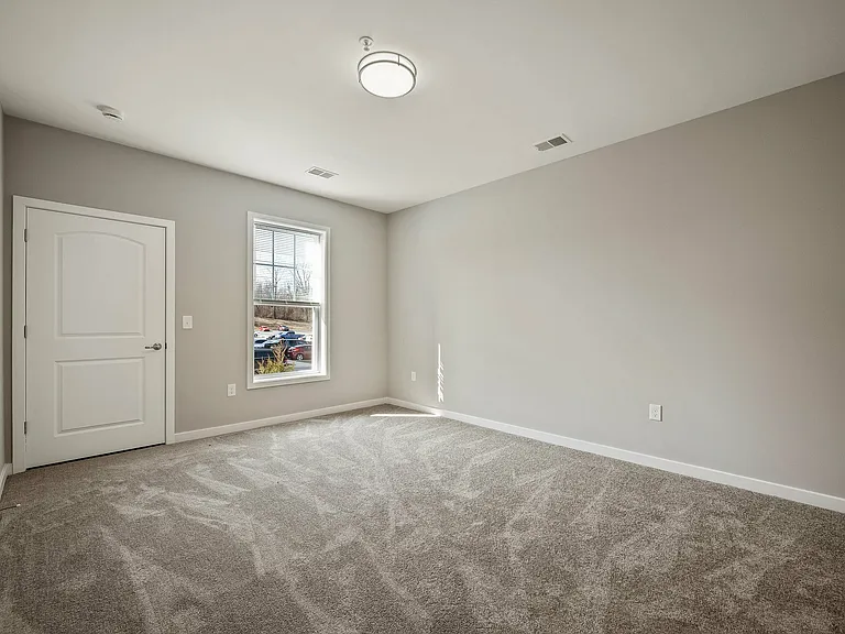 Experience comfort with this sunlit room featuring plush carpeting and a serene ambiance.