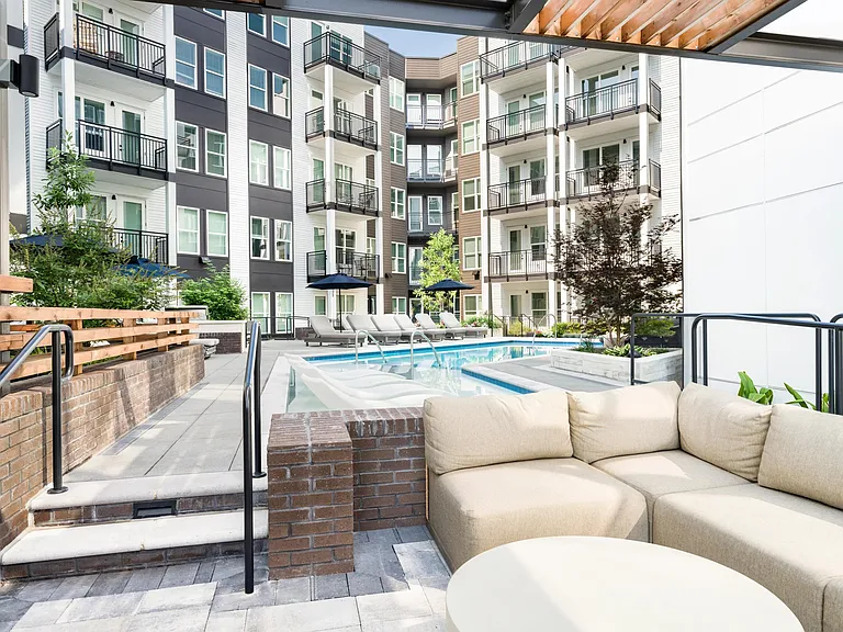 Covered outdoor lounge overlooking the pool courtyard, with cushioned seating, shaded areas, and inviting spaces for conversation and downtime.