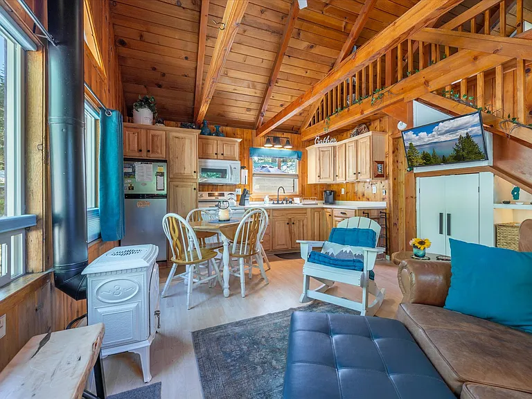 Main living area, dining, kitchen with vaulted ceilings, knotty pine wood accents and gas stove.