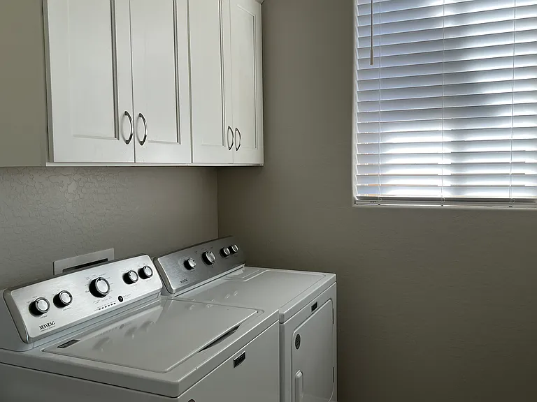 Spacious Inside Laundry Room has White Cabinets, Washer & Dryer