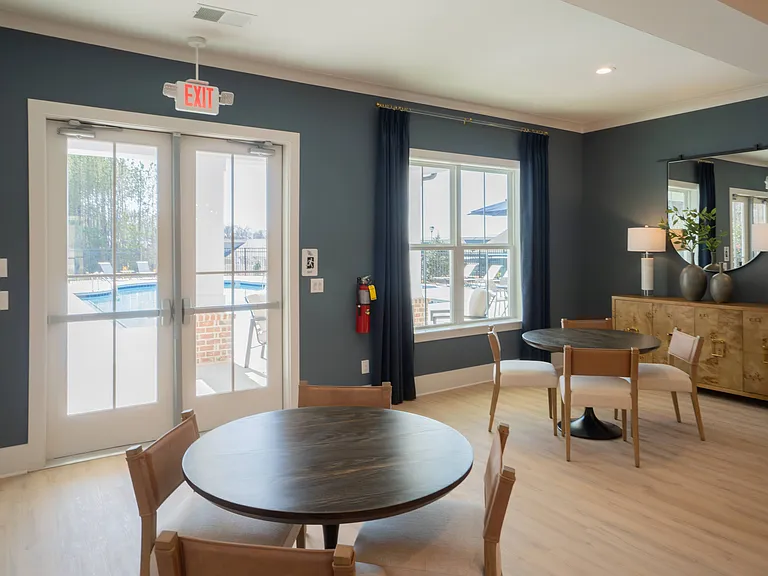Clubhouse living room with additional table seating, looking onto the pool deck.