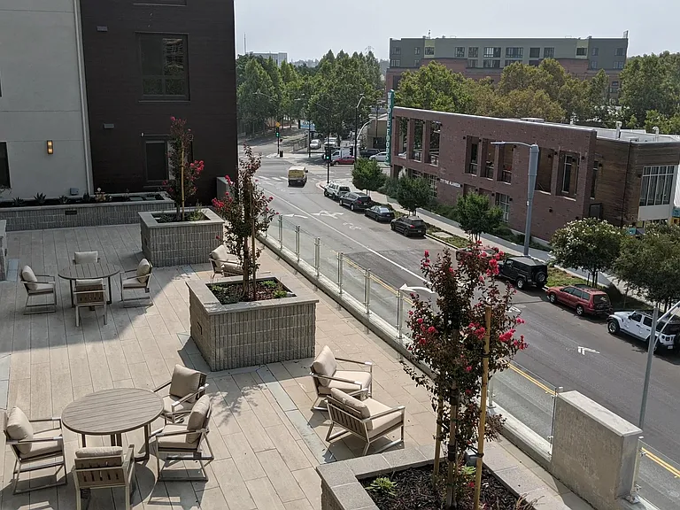 Rooftop terrace with seating, planters, and open views offering a comfortable spot to enjoy the neighborhood.