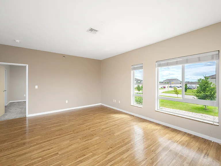 Bright and airy living room with large windows, stylish hardwood floors, and neutral walls, offering a serene view of the outdoors. Bright and airy living room with large windows, stylish hardwood floors, and neutral walls, offering a serene view of the o
