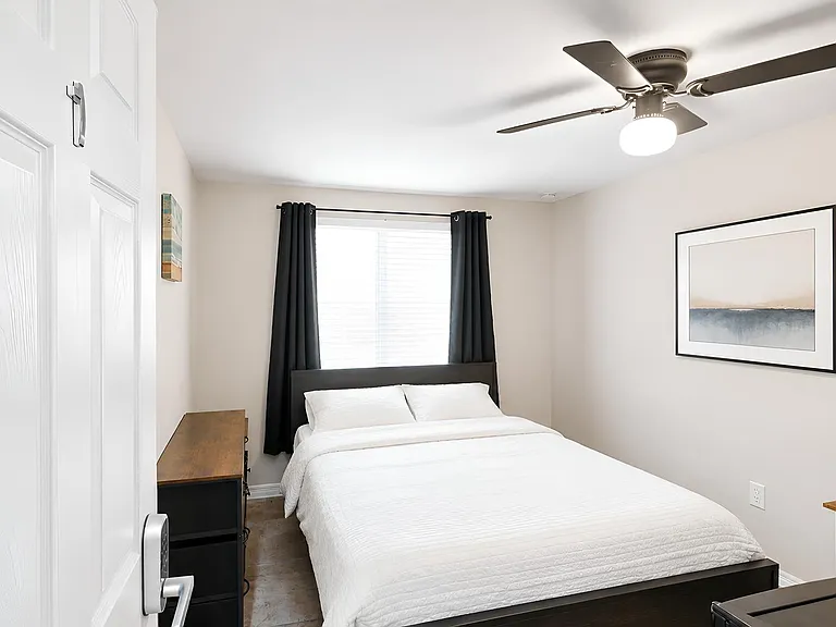 Furnished bedroom with a full bed, closet storage, ceiling fan, and a desk area for work or study.