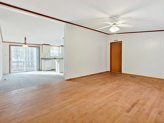 view from entryway. living room in foreground, eat-in kitchen behind. walk-out sliding door to deck. door to main suite.