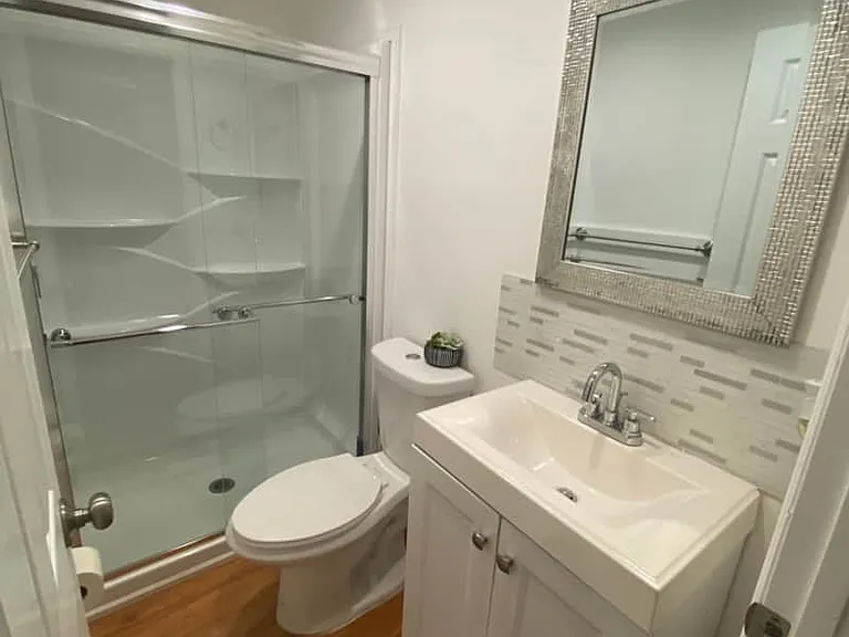 Well-appointed bathroom equipped with a toilet, shower, mirror, and storage cabinet.