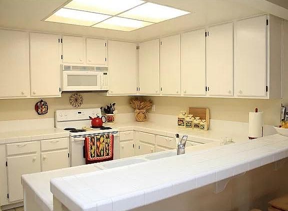 Kitchen with newer microwave and oven (not shown) to the left of the stove top. All white newer appliances with large refrigerator.