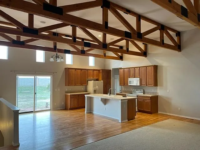 Opposite view, showing kitchen, walk-out to yard and beamed ceiling.