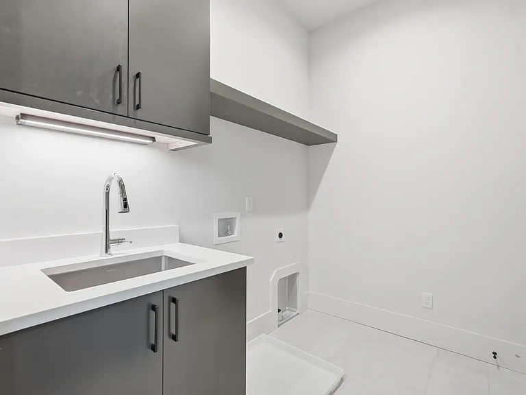 Modern laundry room with built-in cabinetry, utility sink, and ample storage space.