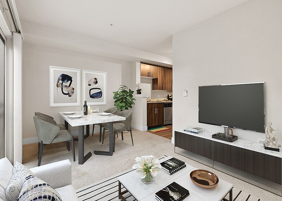 Staged dining and living room with sliding glass doors adjacent to kitchen with stainless steel appliances.