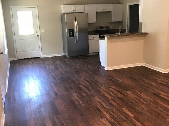 From living space looking towards side door and outdoor grilling patio. Kitchen ahead. Front door to left