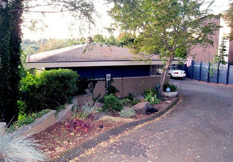 House as seen from the driveway. Covered parking to the right. Photo taken facing north.