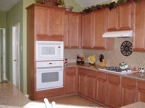 Kitchen has tiled floors and backsplash, 42" cabinets, solid-surface counters.