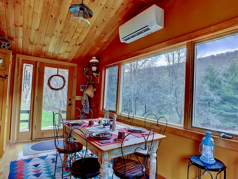 Entrance to Grandview Cabin and Dining Area with large picture window with casement windows on both side and heat pump on the wall.