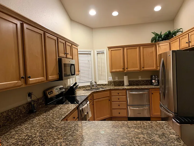 Kitchen with generous storage, bar with seating and stainless appliances (refrigerator, microwave, dishwasher, oven)