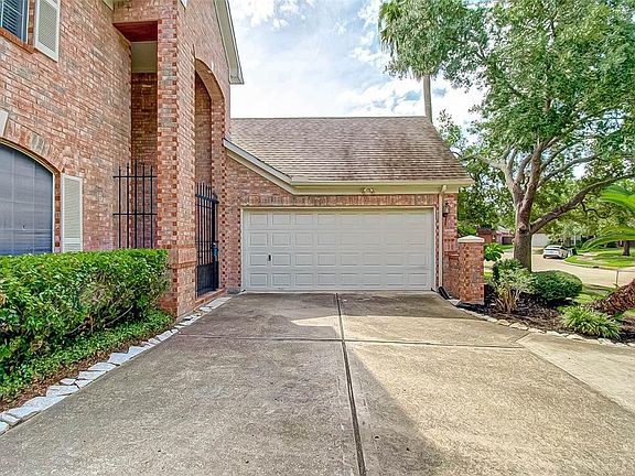 View of 2 car attached garage and wrought iron privacy gate at front of home. Electrical breaker panel located inside garage makes it very convenient when need to access.