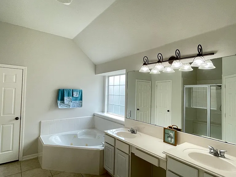Primary bath features dual vanities, jetted tub, separate shower, and spacious walk-in closet