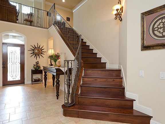 As you enter this home you are greeted with views of the open living room and wood staircase with rod iron railings.