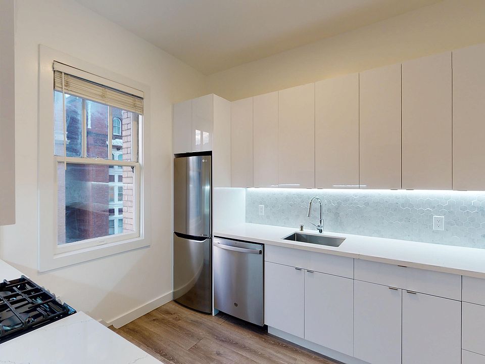 Kitchen with cabinets, stainless appliances, hex tile backsplash, and wood floor