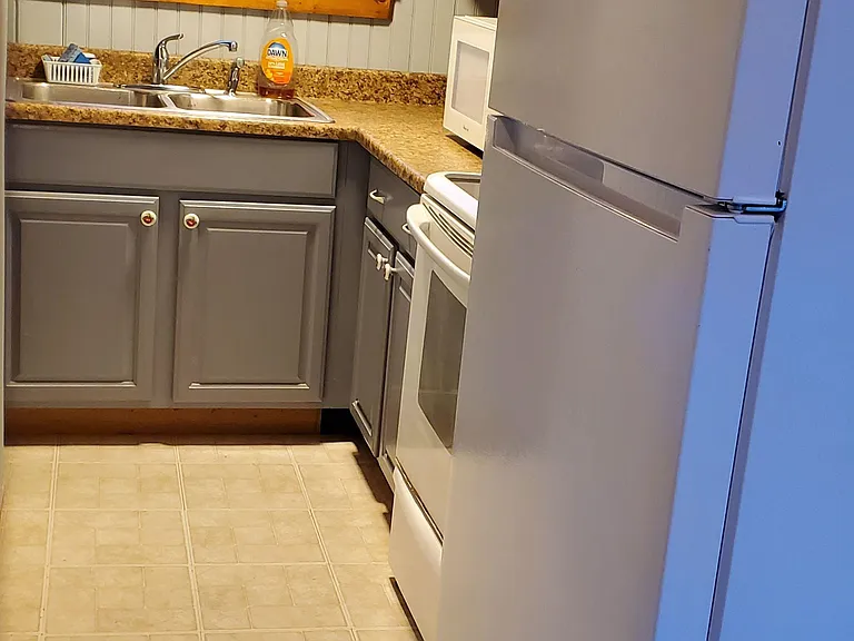 Compact kitchen with ample counter space, upper/lower cabinets, and a full appliance set including fridge and range.