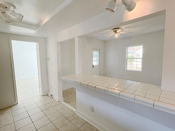 View of Kitchen with Livingroom in background. Door in the middle background leads to small porch in backyard. Door to Bedroom 1 located on left side of picture.