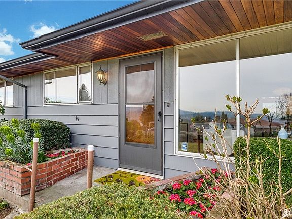 Covered front porch with classic 50s brick planter boxes and big picture window to greet your guests.