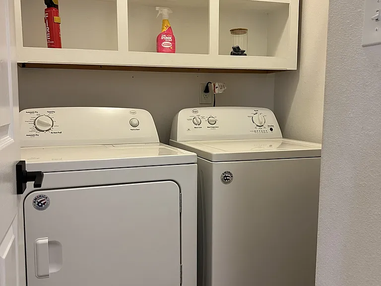Convenient laundry room complete with full-size washer, dryer, and built-in shelving.