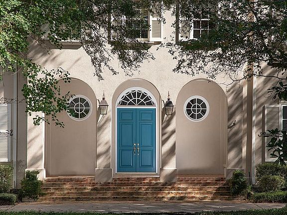 The blue doors pop against the landscaping and the light color of the house.