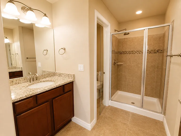 En suite bath with dual facing vanities, walk-in shower, and a separate water closet.