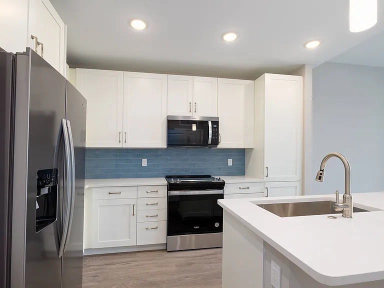 Imperial Crossing Luxury Apartment Homes unit showing a modern kitchen with stainless steel appliances and white cabinets.