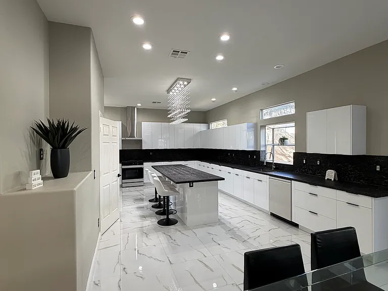 Contemporary kitchen with expansive granite island, European-style high-gloss white cabinetry, and clean-lined finishes.