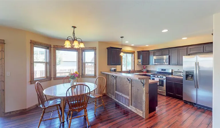 A dining set for four, ample lighting and large windows brighten up the kitchen.