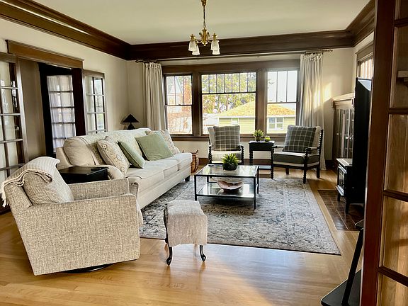 Spacious living room, white oak flooring with herringbone pattern in corners, original windows and VGF trim, french doors.