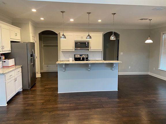 Open kitchen, granite counters, entry left to two car garage, half bath & laundry room entry to right primary bedroom