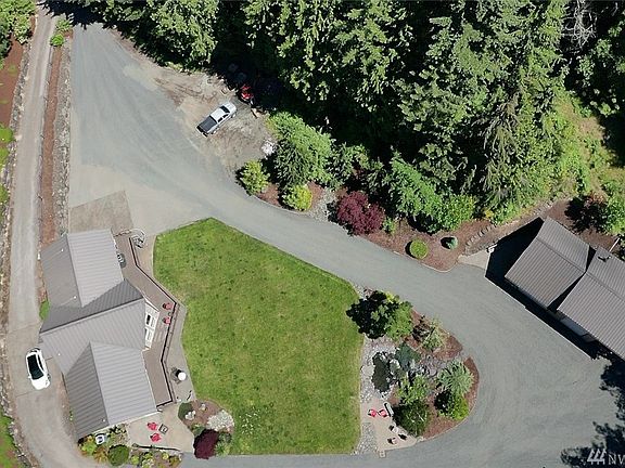 Drone shot showing driveway coming in and tons of parking, shop, water feature sitting area