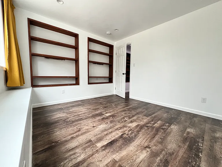 Bedroom 1 with built-in shelves. Natural light from extra large 2 windows facing the backyard. Wake up to the rising sun.