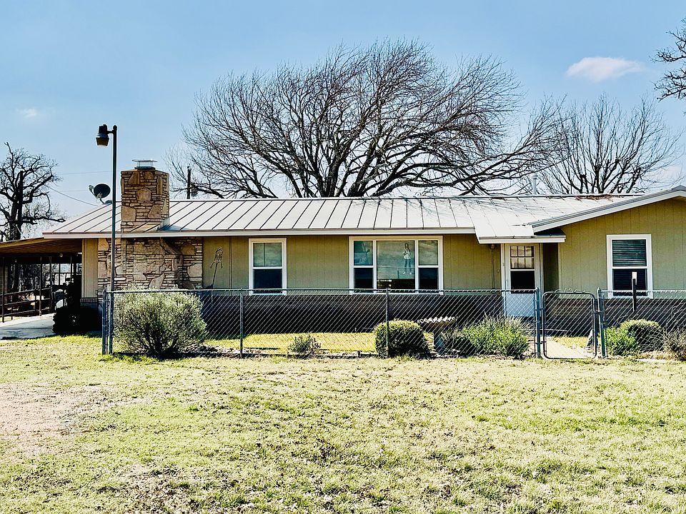 Single carport attached to house. An additional workshop with carport is to the left of the house.